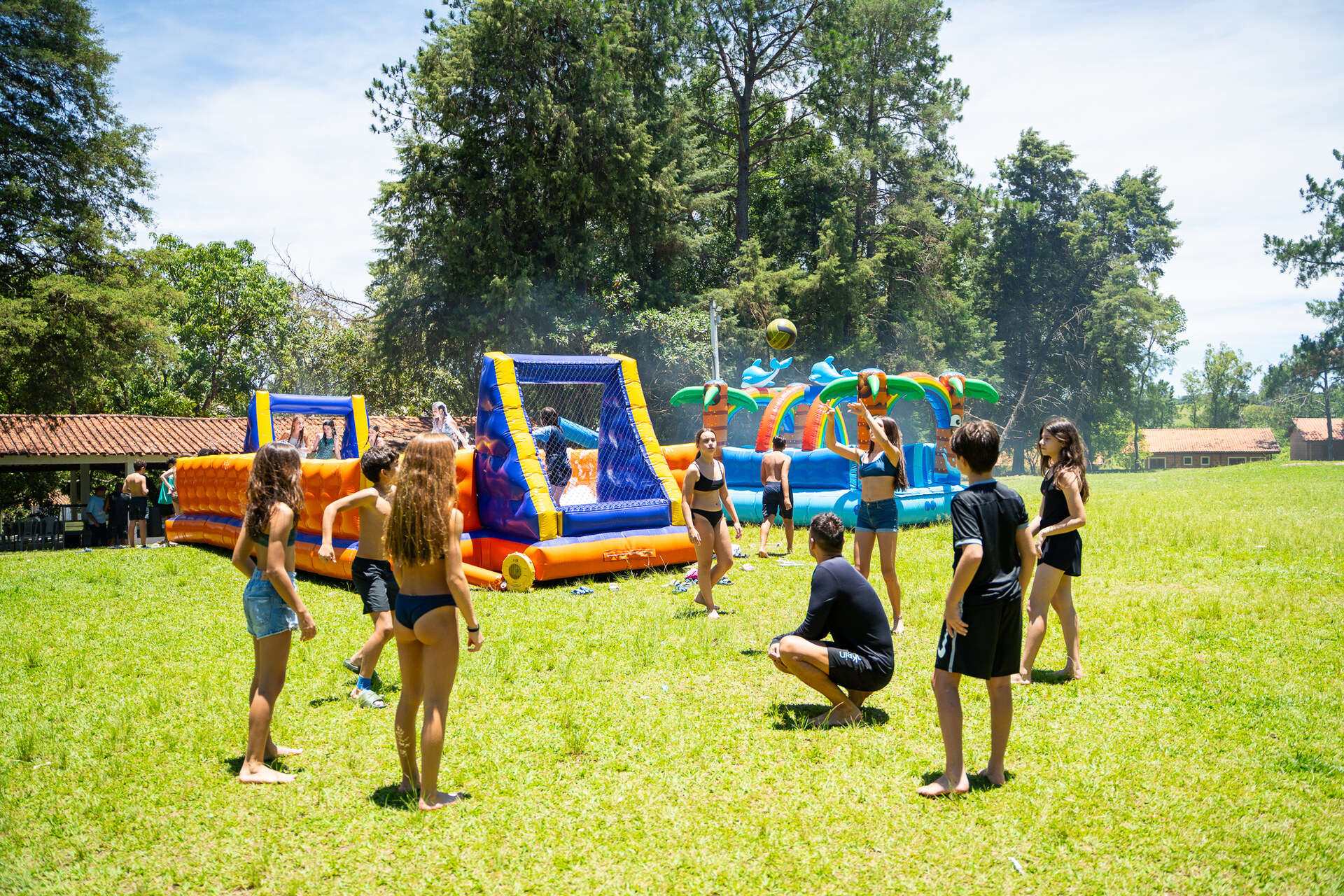 Grupo jogando vôlei ao lado dos infláveis aquáticos